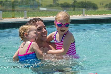 Two girls having fun in the pool with their dad