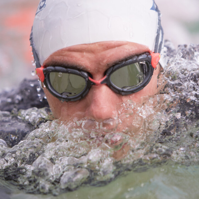 close up of a man swimming in open water with mirrored goggles