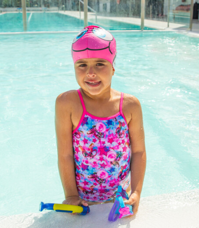 girl in swimming pool with pool toys