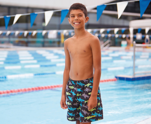 Boy wears a blue swim short and is jumping