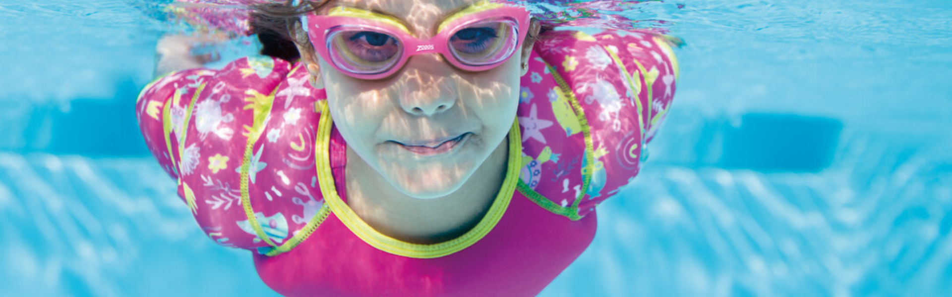 young girl in water wings vest and air cushion goggles